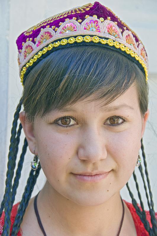 Uighur girl with plaited hair and traditional embroidered hat.