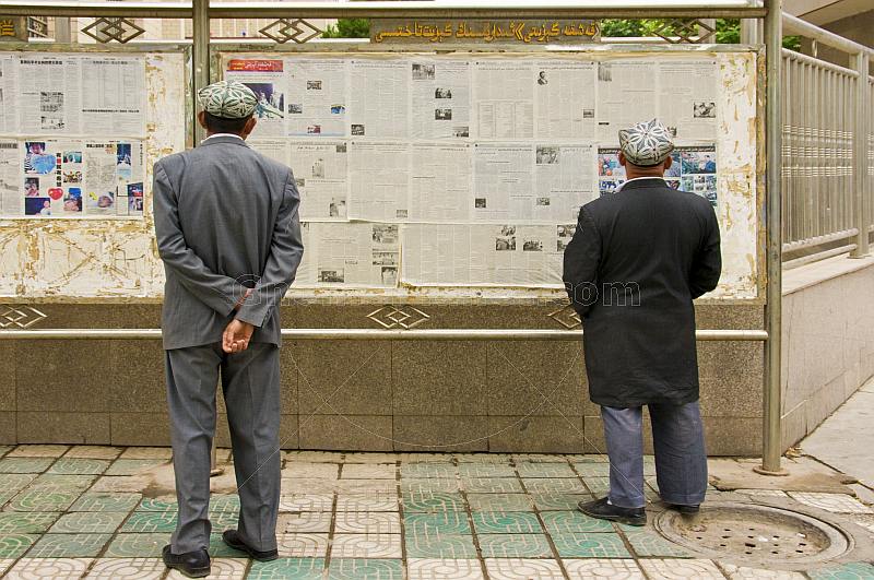 Two Uighur men read the local-language newspapers.