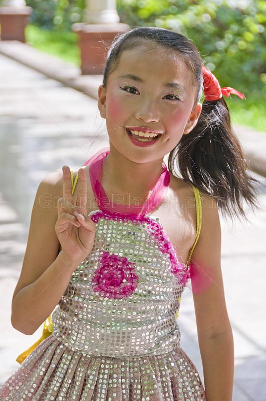 Smiling Chinese girl with party makeup, in sequinned dress.