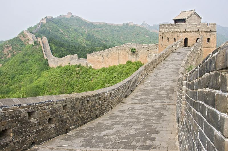 The Great Wall of China crossing forested mountain ranges.