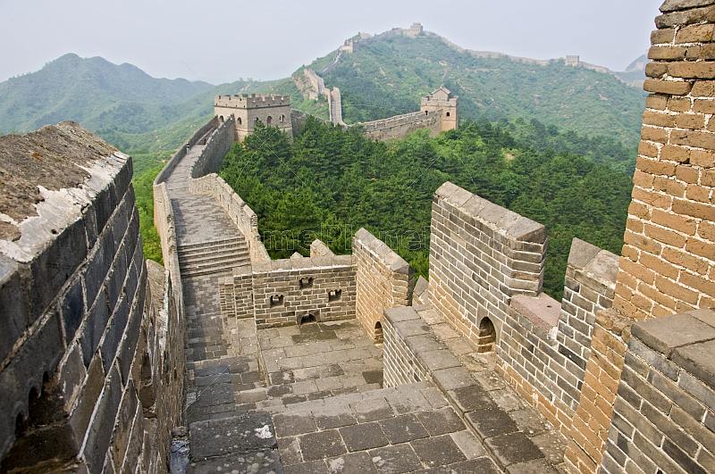 The Great Wall of China crosses forested mountain hillside.