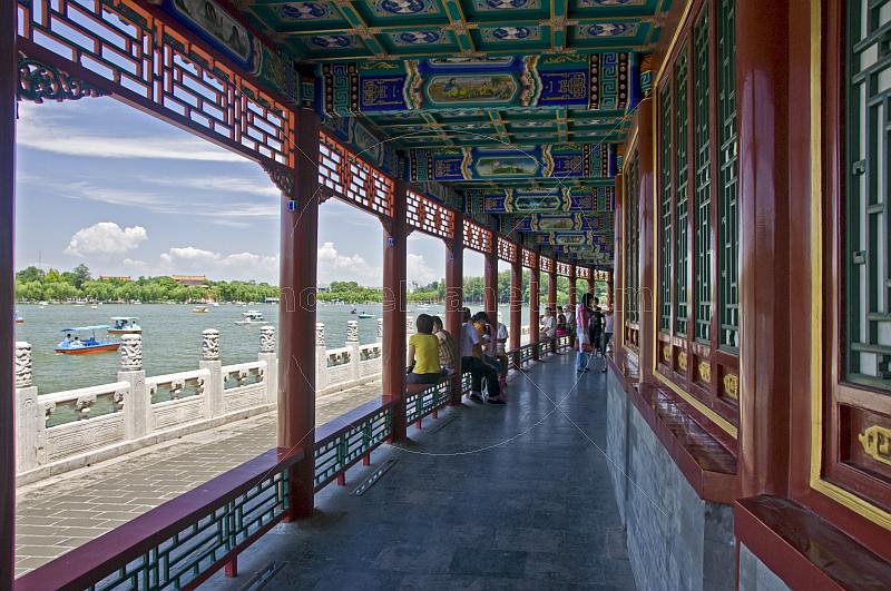 Chinese tourists sit in painted colonade at Beihai Lake.