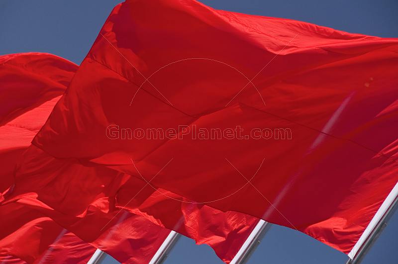 Red Chinese flags billowing in the wind of Tiananmen Square.