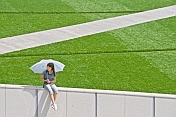 Girl with parasol sits on a wall near the Inner Mongolia Museum.