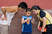 Two Chinese tourists examine their son\\'s digital camera in the Forbidden City.