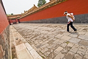 Chinese tourist woman carrying child down a passage to the Imperial Living Quarters in the Forbidden City.