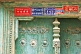 Image of Red and blue signs with Chinese and Uighur writing, on a green door.