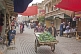 A trader pushes a cart of cucumbers down a busy street in the old city.