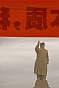 Statue of Chairman Mao Tsedong under red banner with Chinese characters.