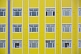 Image of Grid of windows in a yellow and blue apartment building.