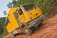 Image of Oasis Overland truck drives through muddy section of jungle logging road.