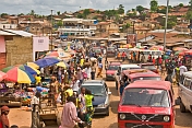 Heavy traffic and colorful market stalls pack the main street.