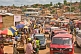 Image of Heavy traffic and colorful market stalls pack the main street.