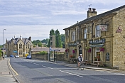 Cylist passes The Postcard public house on the Huddersfield Road A6024.