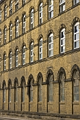 Windows and sandstone wall of old West Yorkshire woolen mill.