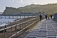 Image of Pedestrians walk beside the sea along the esplanade in Autumn sunshine.